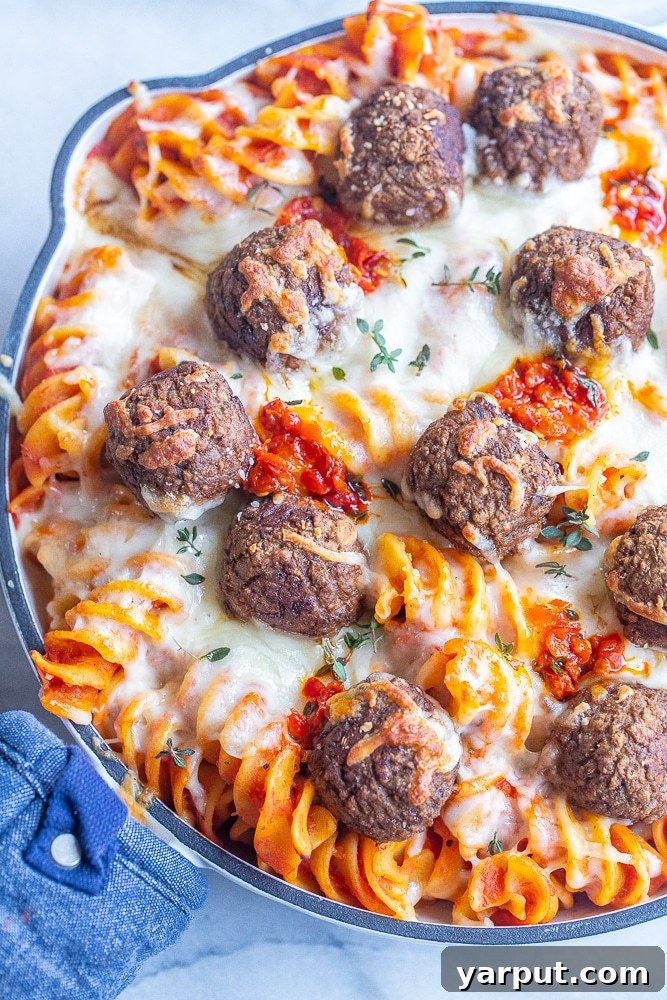 Boldly Spiced Baked Pasta and Plant-Powered Meatballs 7 An overhead shot of a pan filled with cheesy vegetarian meatball baked pasta, garnished with fresh Calabrian chili peppers for a pop of color and extra spice