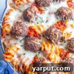 A pan of spicy baked pasta with vegetarian meatballs garnished with Calabrian chili peppers