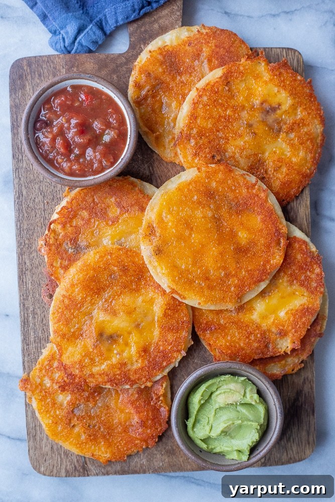 A rustic wooden cutting board overflowing with golden, perfectly-crisped mini cheese crisps, accompanied by vibrant bowls of fresh salsa and creamy guacamole. The scene highlights their irresistible texture and perfect pairing with dips.