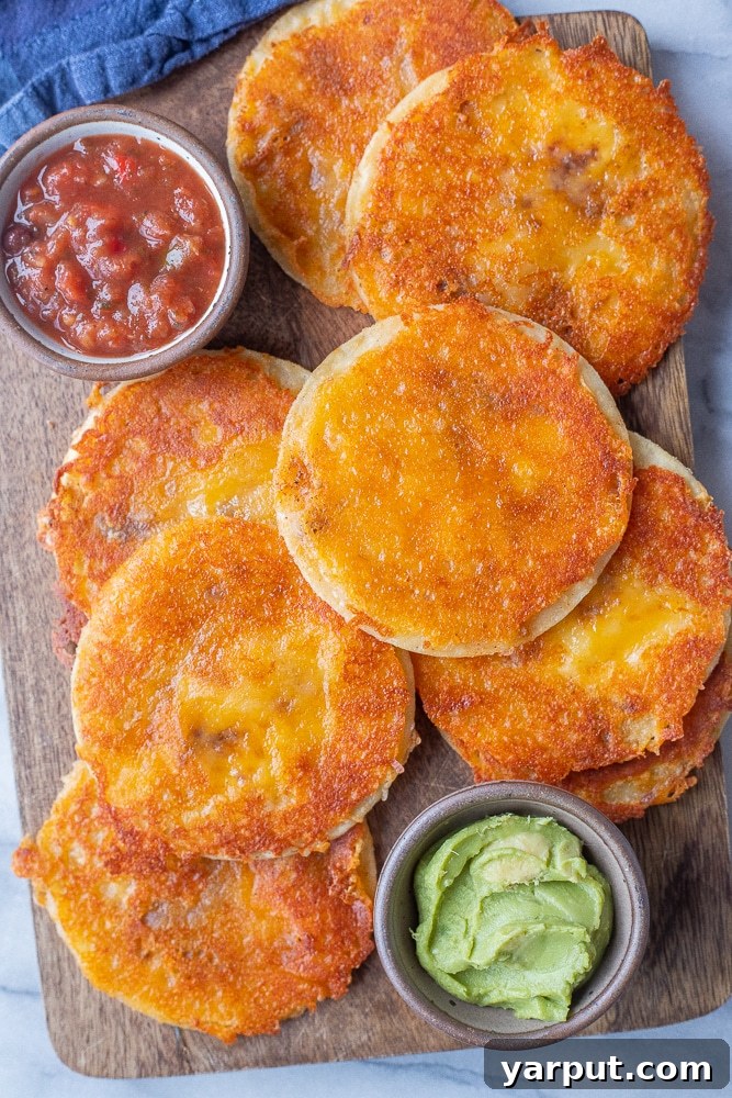 An appetizing close-up of vegetarian cheese crisps artfully arranged on a cutting board, surrounded by bowls of fresh, vibrant dipping sauces like guacamole and salsa, showcasing their irresistible appeal.