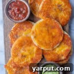 A small, circular, golden-brown cheese crisp, perfectly crispy and appetizing, set against a light background.