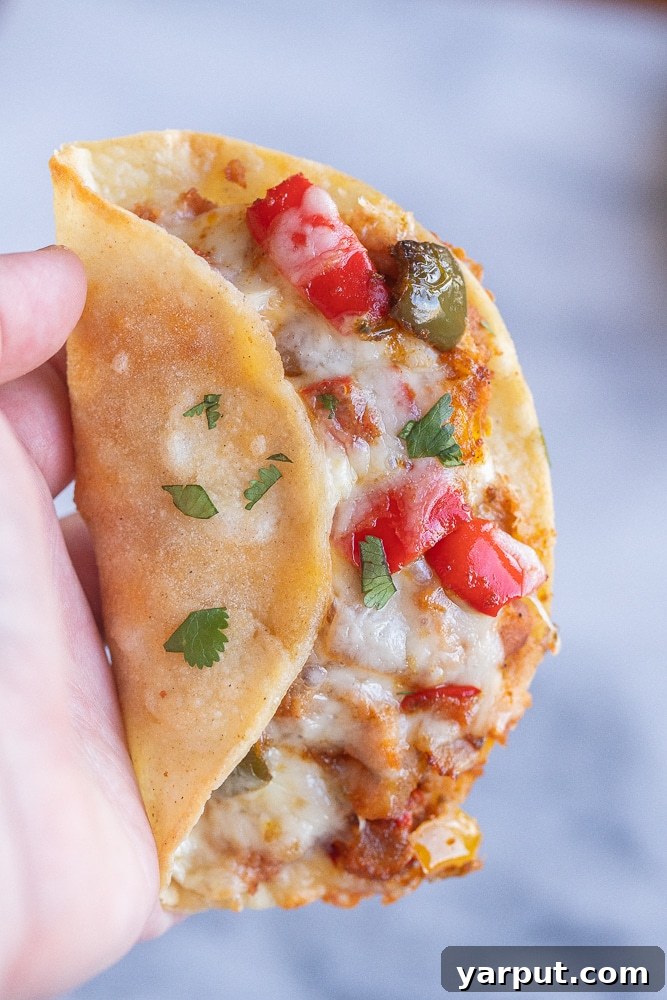 Crunchy Oven-Baked Fajita Tacos 6 a hand holding a close up crispy baked fajita taco