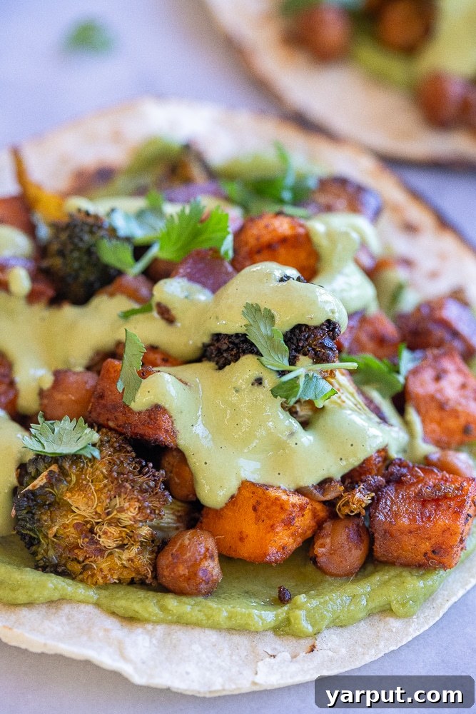Vibrant Roasted Veggie Tacos with Emerald Tahini 6 A vibrant close-up shot of a roasted vegetable taco with a generous amount of green cilantro lime tahini sauce and fresh cilantro, highlighting its fresh ingredients.