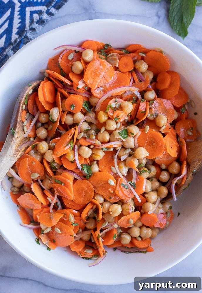 Maple Orange Glazed Carrot & Chickpea Medley 2 fresh carrot and chickpea salad in a bowl with a wooden spoon