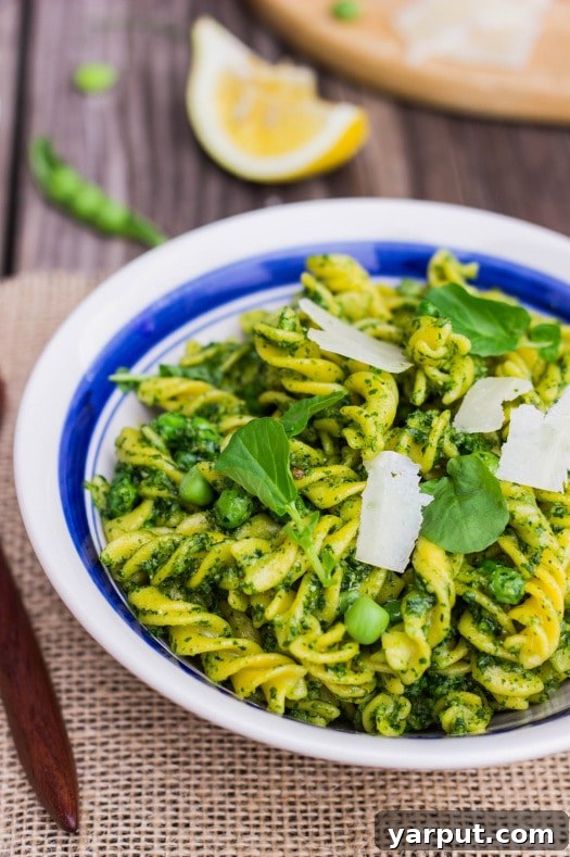 Affordable Vegetarian Meal Plan for Week 12 4 Vibrant watercress pesto pasta with peas in a bowl, garnished with herbs.