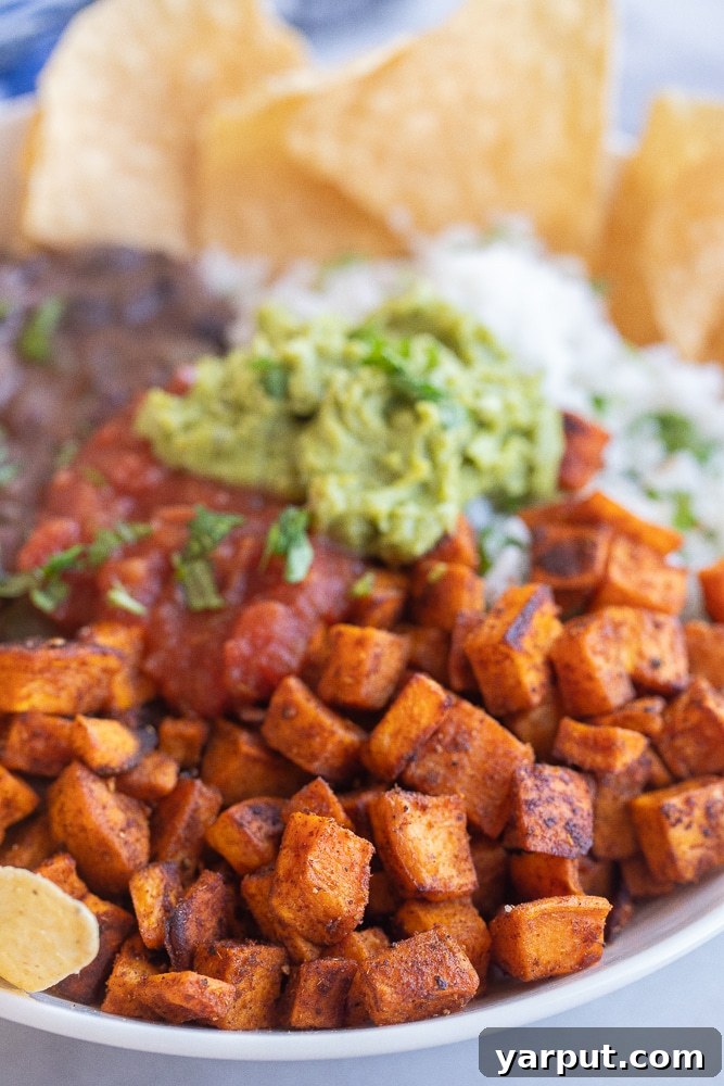 Roasted Sweet Potato and Black Bean Power Bowls 5 A close-up view of a vegetarian burrito bowl, highlighting the perfectly roasted sweet potato cubes nestled among black beans, rice, and fresh toppings.