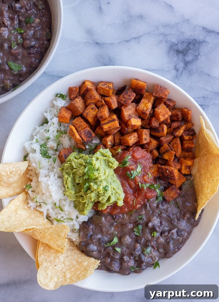 Roasted Sweet Potato and Black Bean Power Bowls 6 A wide shot of several Roasted Sweet Potato and Black Bean Burrito Bowls, garnished with fresh cilantro and served with a side of crispy tortilla chips.