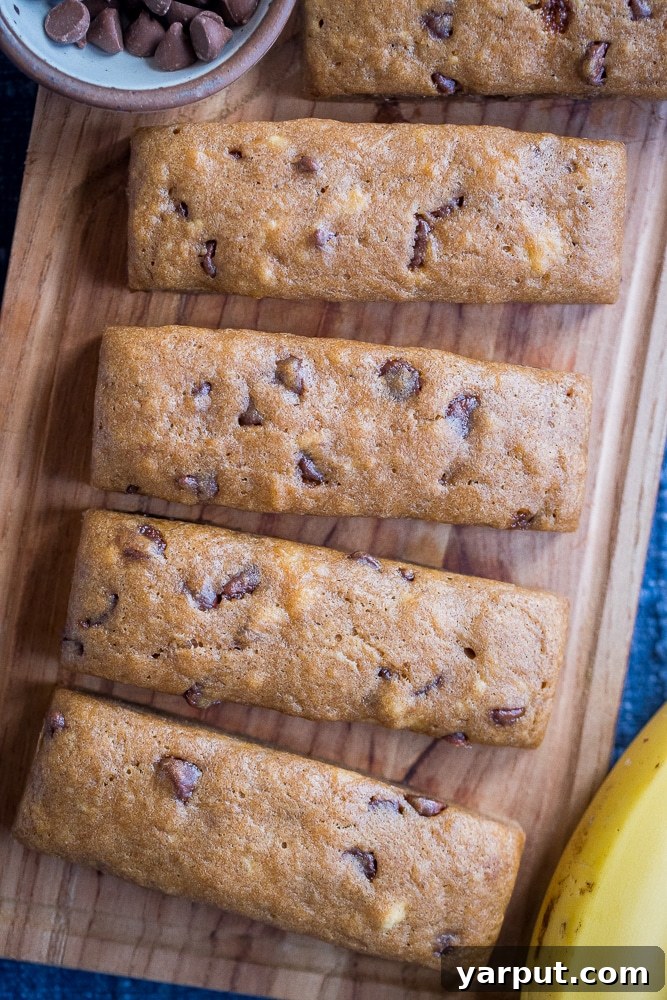 Ultimate Chocolate Chip Banana Bread Bars 2 Delicious Chocolate Chip Banana Bread Bars on a wooden cutting board, ready to be enjoyed.