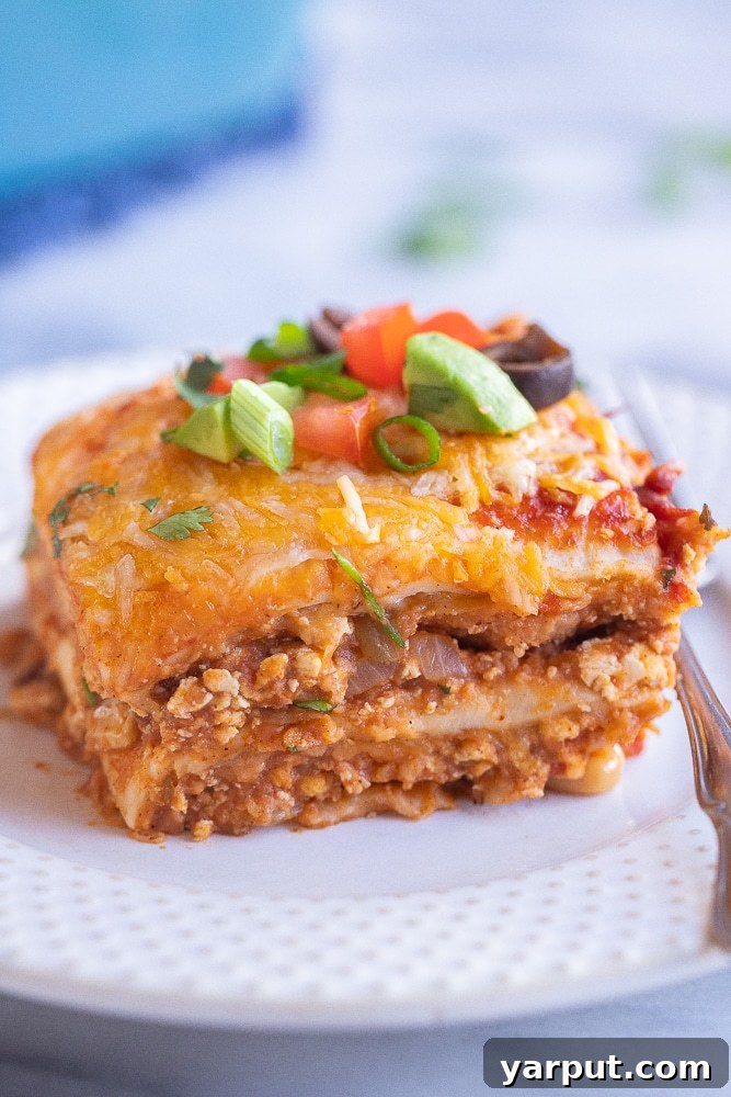 Zesty Veggie Taco Bake 5 A close-up shot of a single slice of Vegetarian Soft Taco Casserole on a plate, showcasing its distinct layers of tortilla, beans, tofu, and melted cheese, garnished with fresh cilantro.