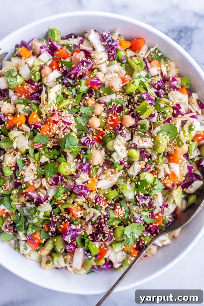 Zesty Asian Cabbage Slaw 5 A beautifully presented bowl of Asian Inspired Chopped Salad, garnished with a sprinkle of toasted sesame seeds and fresh green herbs, ready to be enjoyed.