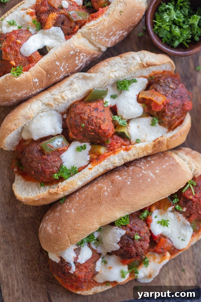 Hearty Plant-Based Meatball Subs 5 Close-up of a single vegetarian meatball sub, beautifully baked with melted mozzarella cheese cascading over the meatballs and vegetables.