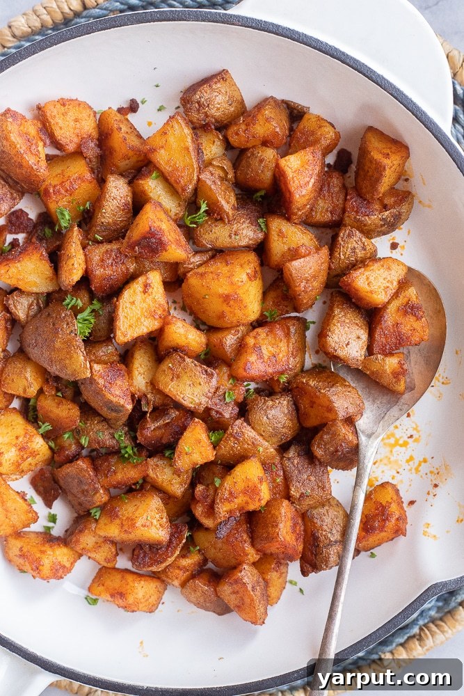 home fries in a pan with a spoon, showing a perfectly browned and crispy texture