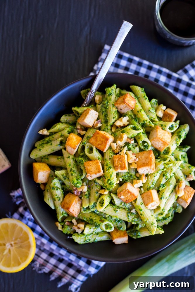 Budget-Friendly Vegetarian Meal Plan - Week 15 5 A plate of vibrant kale and leek pesto pasta with cubes of tofu, a healthy and delicious vegetarian meal.