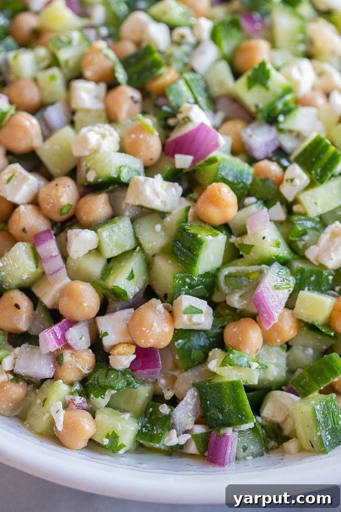 Fresh Herby Cucumber, Feta, and Chickpea Salad 6 A top-down shot of the finished Herby Cucumber Salad with Feta and Chickpeas in a rustic bowl, with serving spoons, inviting enjoyment.