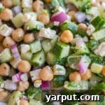 Herby Cucumber Salad with Feta and Chickpeas in a bowl, with fresh herbs and a print recipe button.
