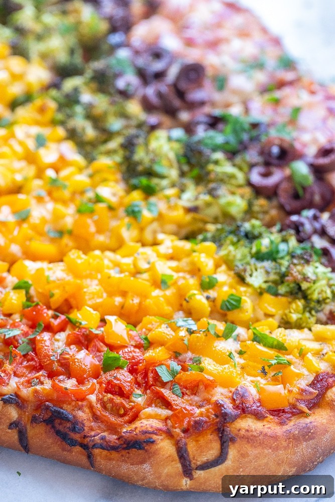 Kaleidoscope Veggie Pizza 5 A close-up shot of the baked vegetarian supreme pizza, showcasing the perfectly melted mozzarella cheese and the beautifully cooked, colorful vegetables arranged in a rainbow pattern. The crust is golden brown and inviting.