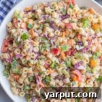Macaroni Coleslaw Salad in a white bowl with a wooden spoon