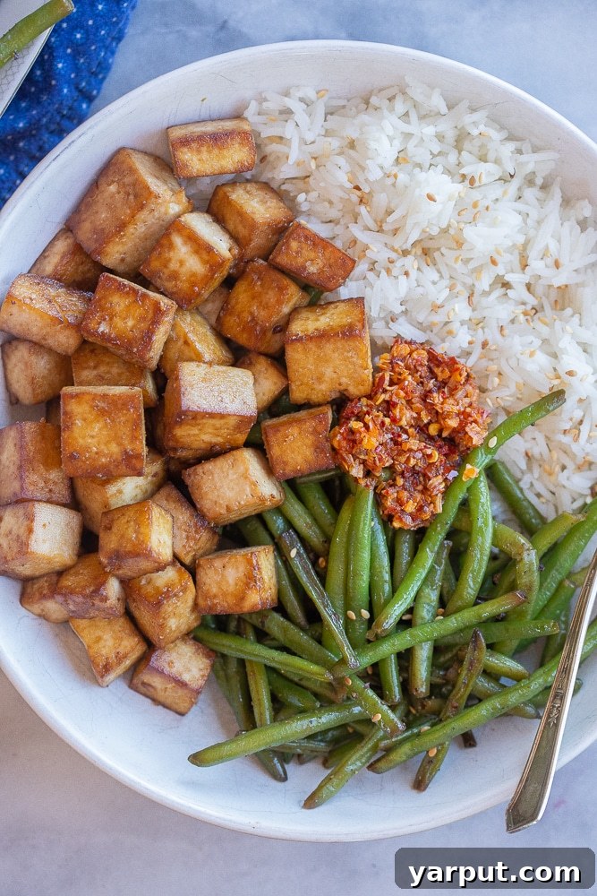 Golden Crispy Pan-Fried Tofu 6 Easy pan-fried tofu served in a bowl with fluffy white rice and vibrant green beans, a complete and healthy meal.