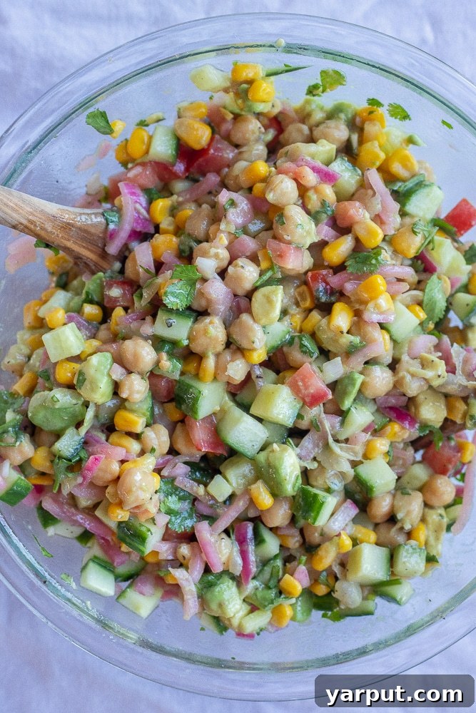 Tangy Avocado and Cucumber Salad with Pickled Onions 4 A large mixing bowl filled with the colorful ingredients for the Pickled Onion and Avocado Salad, including cucumber, corn, tomatoes, chickpeas, avocado, and pickled red onions, all ready to be tossed together with the dressing.