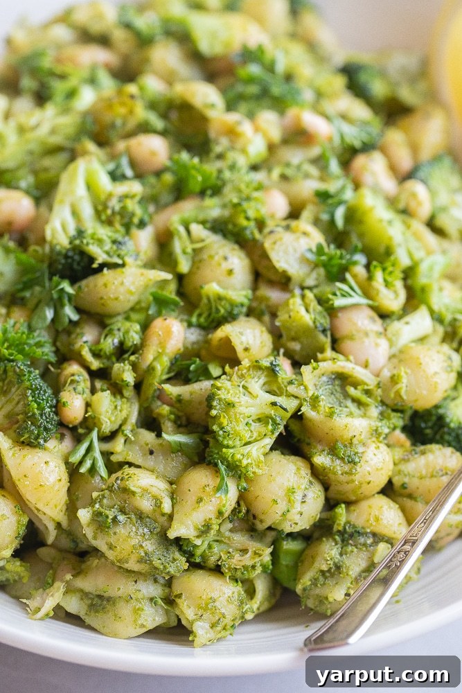 Vibrant Pesto Pasta with Broccoli and Cannellini Beans 6 Close up of a bowl of pesto pasta with broccoli and white beans, garnished with fresh lemon