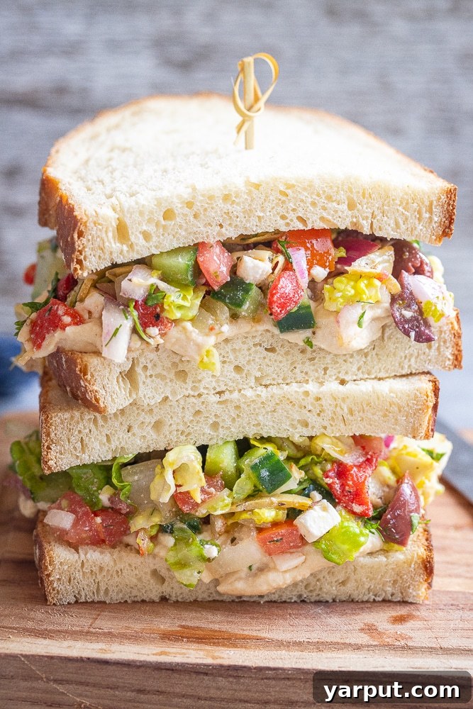 Zesty Greek Hummus Sandwiches 2 Two vibrant Greek Salad Sandwiches stacked on sourdough bread, showcasing fresh ingredients and creamy hummus.