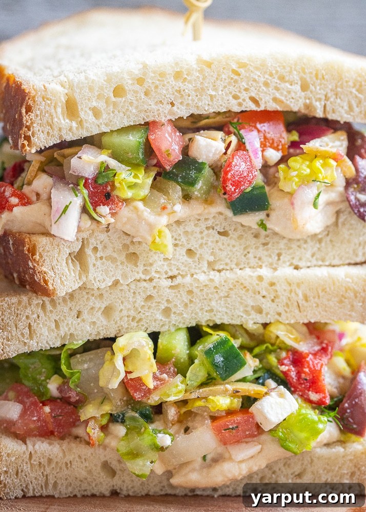 Zesty Greek Hummus Sandwiches 6 A close-up shot of a Greek Salad Sandwich, showing the textures of the fresh salad and creamy hummus on sourdough bread.