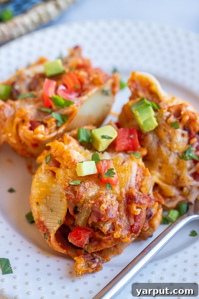 Close-up of a single vegetarian chili cheese stuffed shell on a plate, garnished with fresh herbs