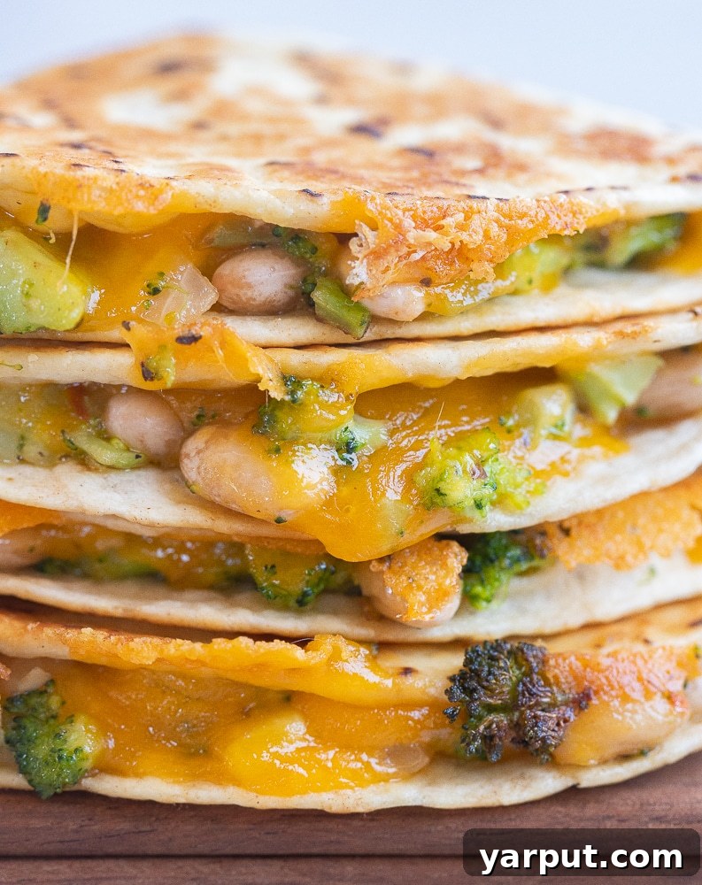Creamy Broccoli, Cheddar, and White Bean Quesadillas 7 Another close-up of cheesy Broccoli Cheddar White Bean Quesadillas stacked, highlighting the melted cheese and hearty filling