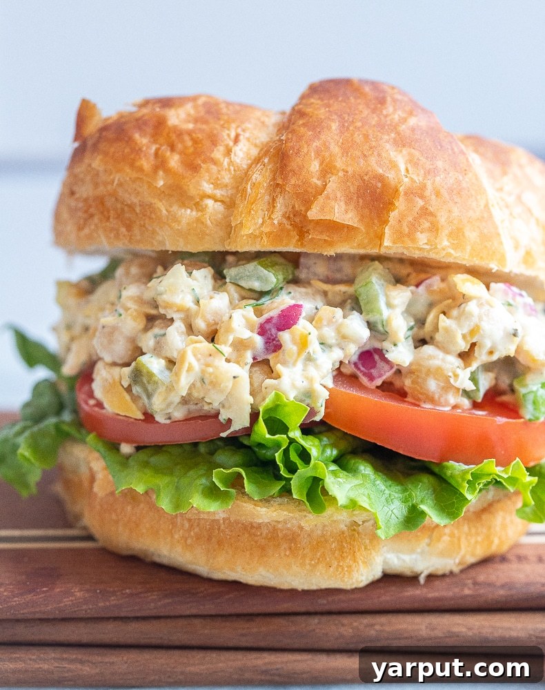 An inviting close-up of a vegetarian tuna salad croissant, revealing the rich, textured chickpea filling nestled within the flaky layers of the pastry, offering a preview of its deliciousness. Perfect for inspiring healthy meal ideas.
