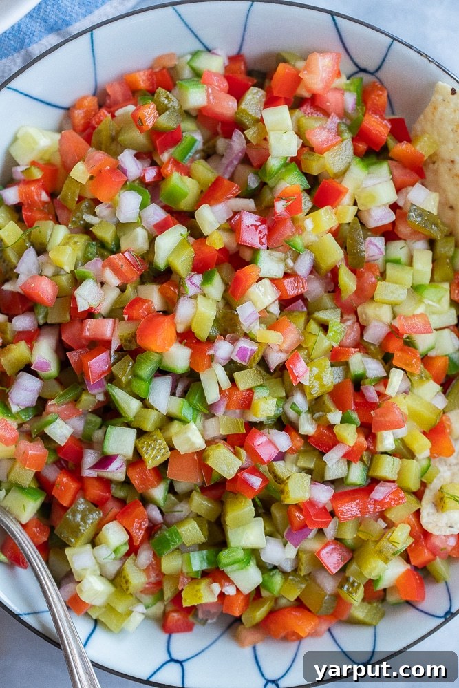 Large bowl of homemade Pickle De Gallo with a serving spoon and tortilla chips, ready to be enjoyed.