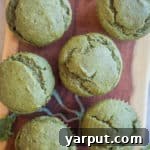 A top-down view of a freshly baked green muffin, showcasing its vibrant color and inviting texture.