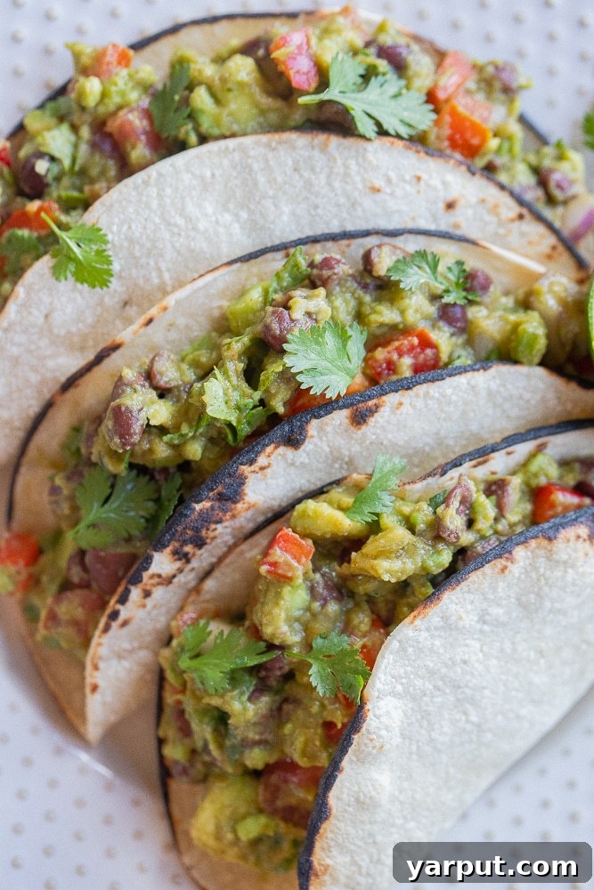 Ultimate Guacamole Tacos 2 Close-up of vibrant, loaded vegetarian guacamole tacos on a plate, showcasing fresh ingredients.