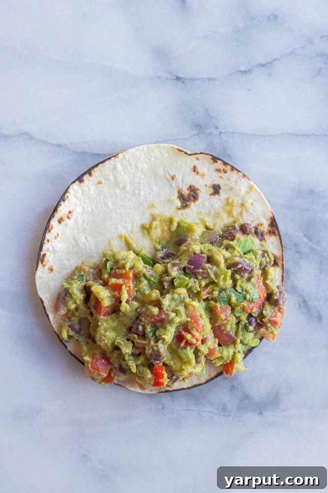 Ultimate Guacamole Tacos 4 A perfectly assembled loaded guacamole taco resting on a rustic cutting board, ready to be enjoyed.