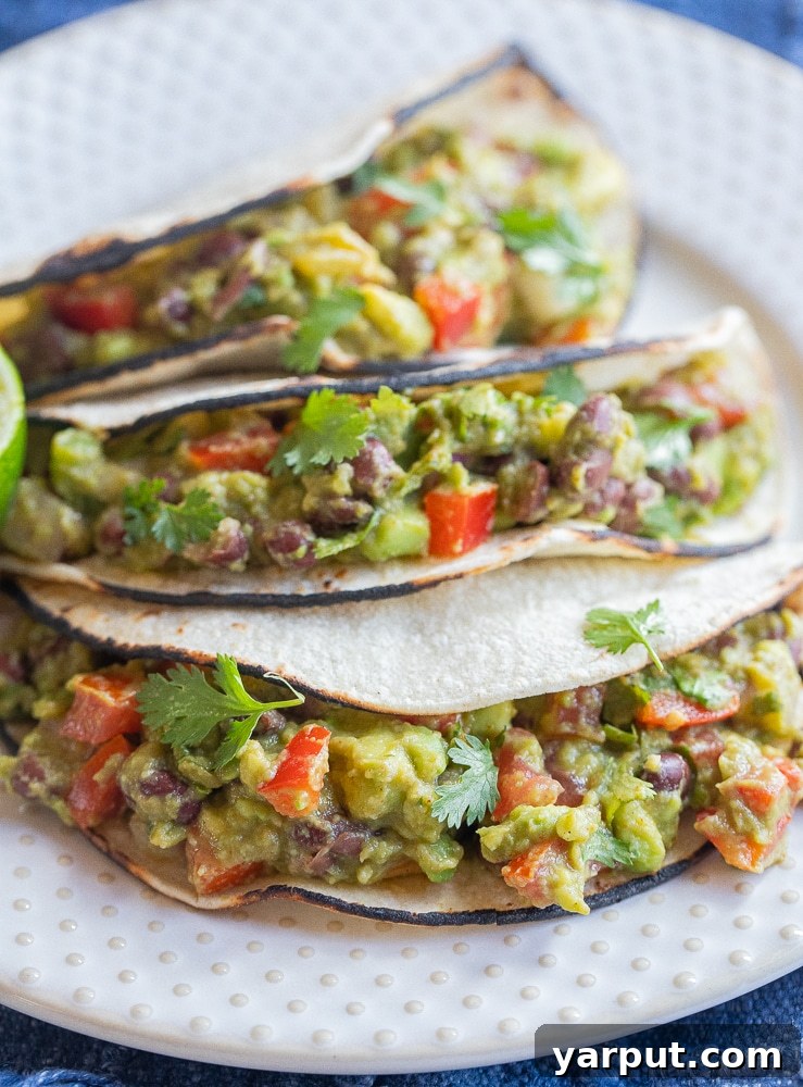 Delicious Loaded Guacamole Tacos with fresh toppings and a side of chips and salsa.