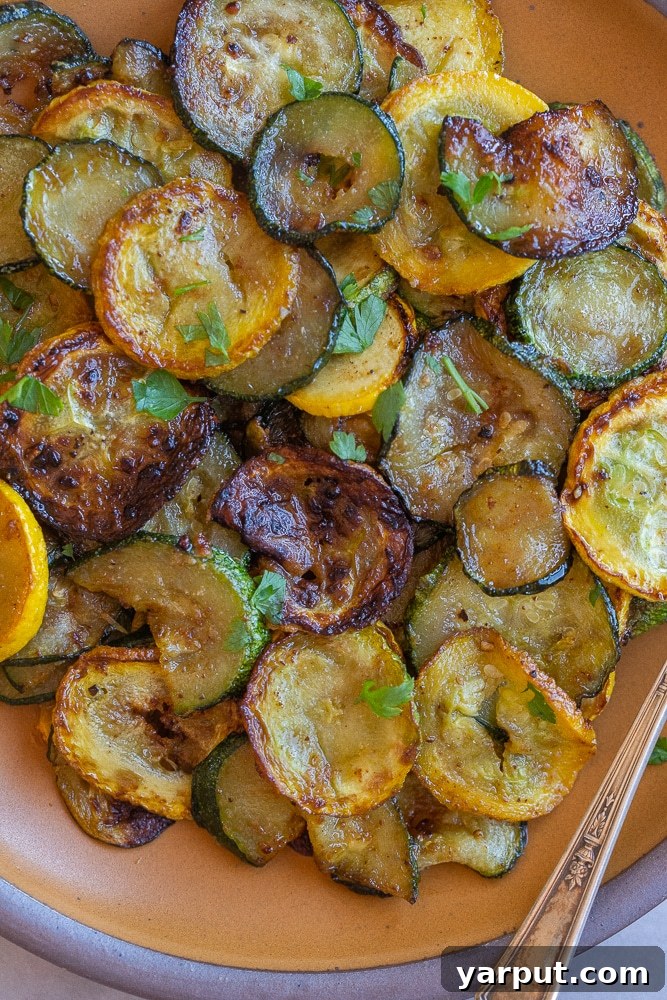 Skillet Caramelized Summer Squash 2 Close up of a plate of glistening caramelized pan-fried summer squash, garnished with fresh herbs.