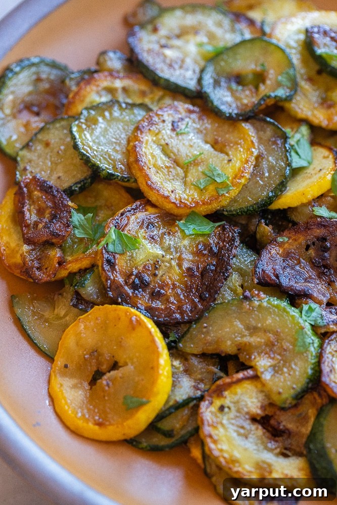 Skillet Caramelized Summer Squash 6 Close up of a single caramelized zucchini slice next to a yellow summer squash slice, highlighting the golden-brown color.