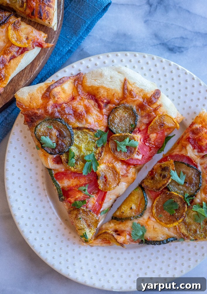 Vibrant Summer Squash and Tomato Pizza 6 A perfectly portioned slice of Summer Squash and Tomato Pizza, showcasing the beautiful golden crust, rich melted cheese, colorful caramelized squash, and fresh tomato, garnished with bright green herbs, ready to be enjoyed.