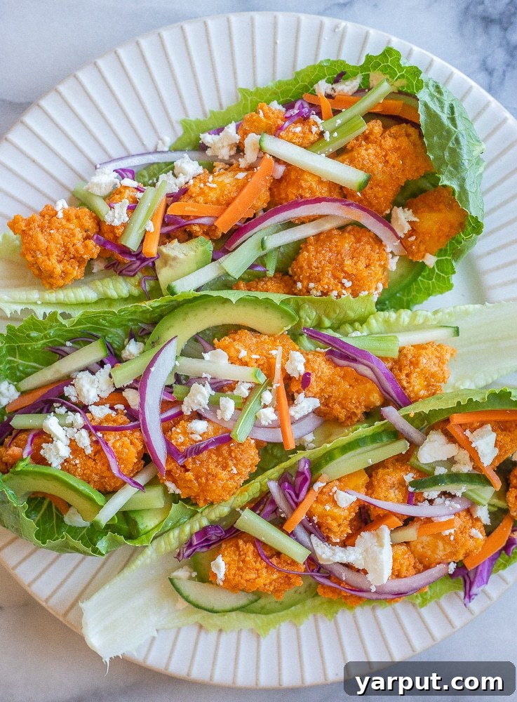 Fiery Tofu Lettuce Cups 5 A beautifully arranged plate featuring three crispy buffalo tofu lettuce wraps, garnished and ready to be enjoyed.