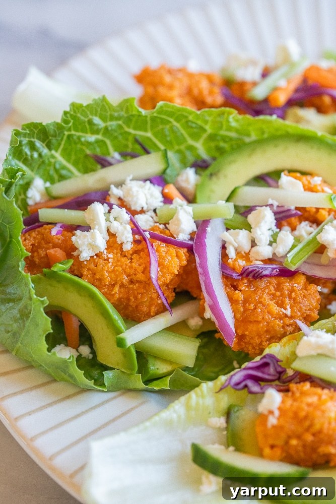 Fiery Tofu Lettuce Cups 6 A close-up view of a single crispy buffalo tofu lettuce wrap, beautifully presented on a plate, highlighting its textures and vibrant ingredients.