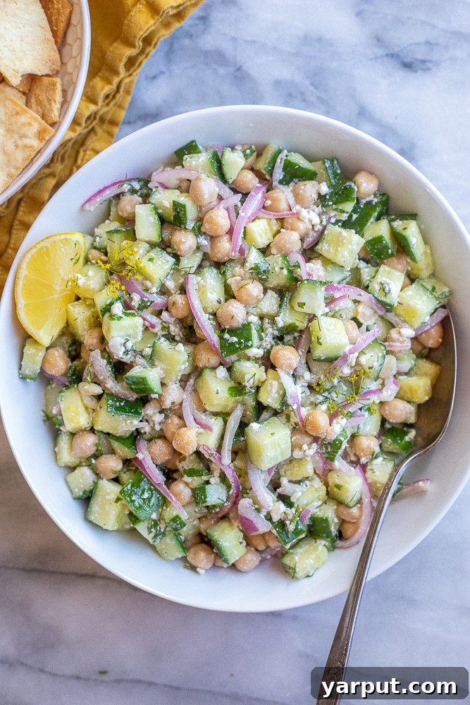 Chickpea cucumber salad in a serving bowl with a fresh lemon wedge on the side