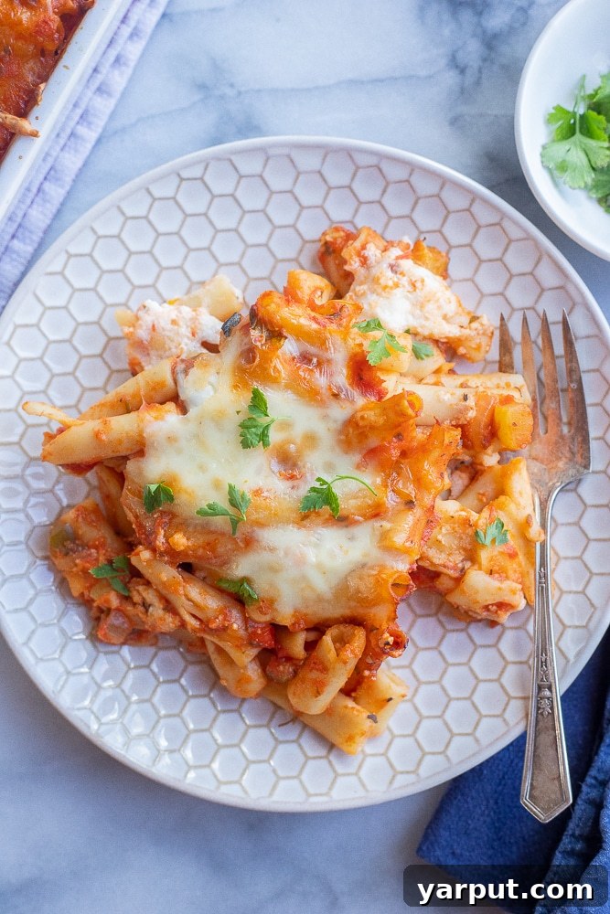 A perfectly portioned plate of Vegetarian Baked Ziti with a fork, ready to be enjoyed. The melted cheese and sauce are visible, inviting a delicious bite.