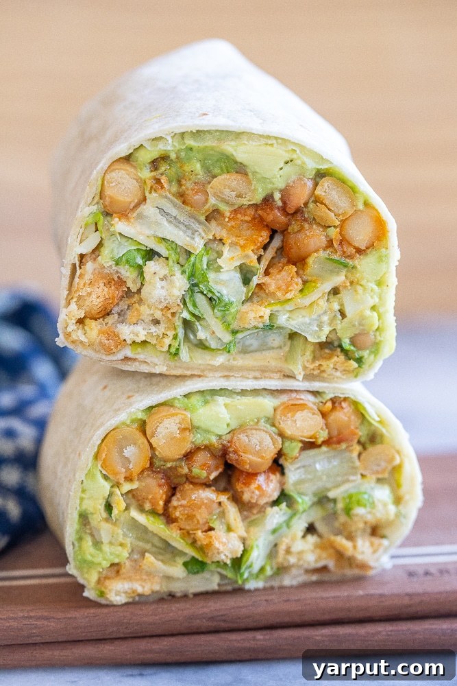two chickpea Caesar salad wraps stacked on top of each other on a cutting board