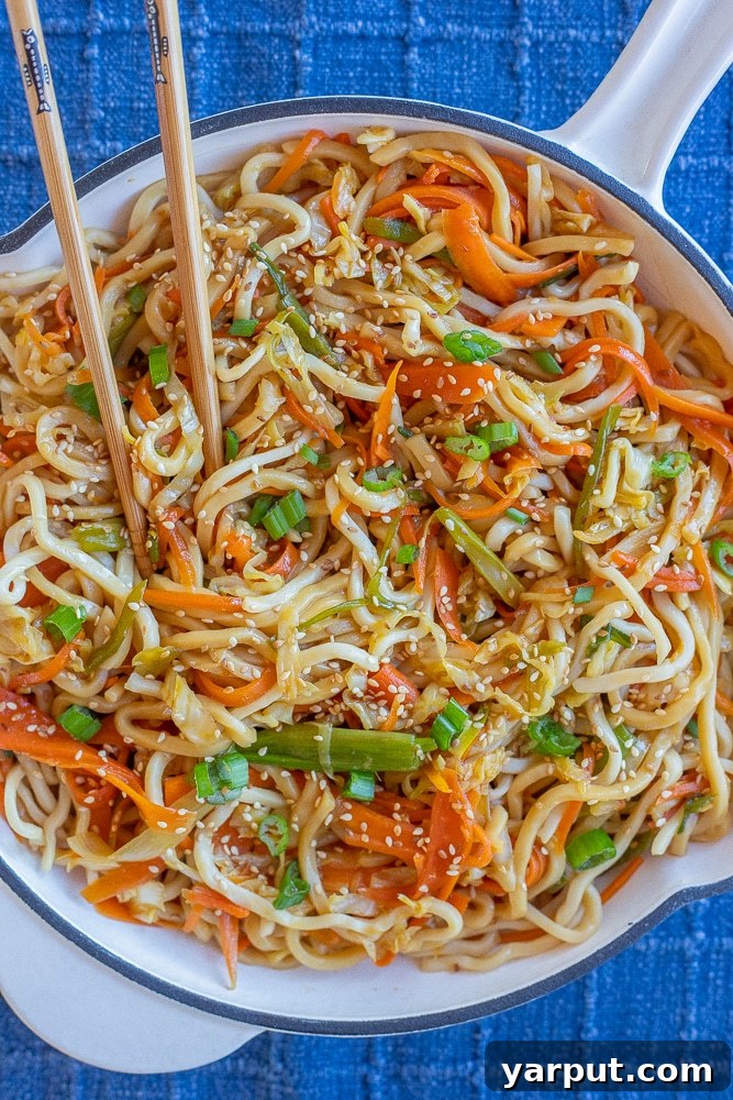 A vibrant bowl of stir-fried noodles with crisp cabbage and colorful carrots, garnished with fresh cilantro, offering a quick and healthy vegetarian meal.