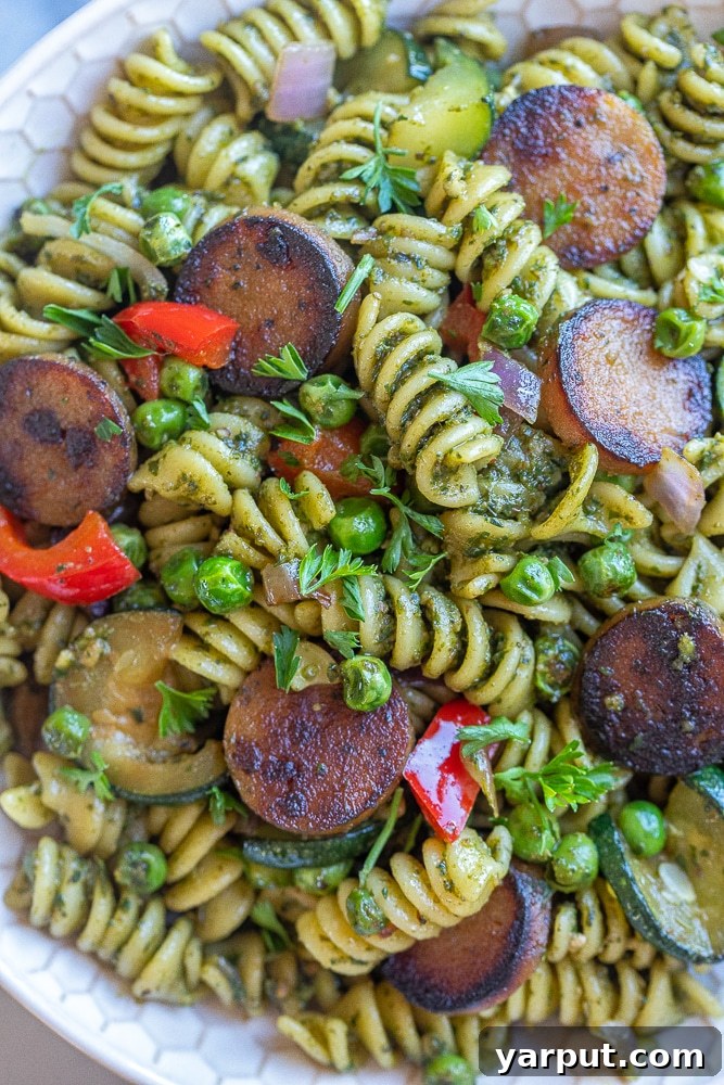 Crispy Sausage Pesto Pasta with Vibrant Vegetables 5 A beautifully plated close-up of crispy plant-based sausage pesto pasta, garnished with fresh herbs, showcasing the vibrant colors and appealing textures.