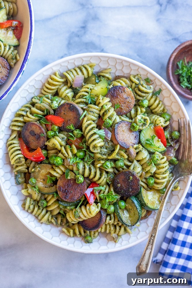 Crispy Sausage Pesto Pasta with Vibrant Vegetables 6 A close-up shot of the finished crispy plant-based sausage pesto pasta with vegetables, highlighting the golden-brown sausage and vibrant green pesto.