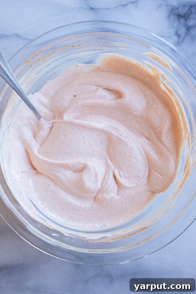 Creamy Zesty Fish Taco Sauce 4 A close-up shot of creamy fish taco sauce in a sleek mixing bowl, garnished with fresh herbs.