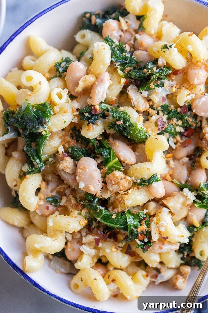 Rustic Kale and White Bean Pasta with Parmesan 5 A close-up shot of a single serving bowl filled with comforting white bean and kale pasta, generously topped with melted Parmesan cheese and fresh garnish, ready to be enjoyed.