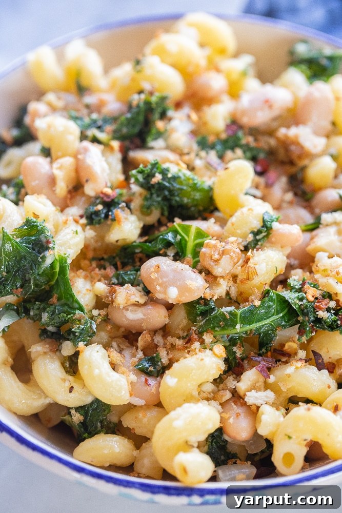 Rustic Kale and White Bean Pasta with Parmesan 6 A close-up, appetizing image of the Kale and White Bean Pasta with Parmesan served in a white bowl, highlighting the texture of the pasta, the vibrant greens, and the melted cheese.