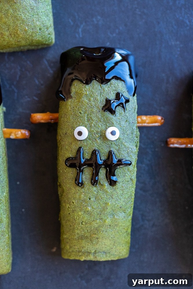 Spooky Smart Frankenstein Treats 2 Adorable, healthy Frankenstein Halloween Bars arranged on a dark background, showcasing their vibrant green color and playful decorations. Perfect for a kid-friendly Halloween treat or healthy snack.