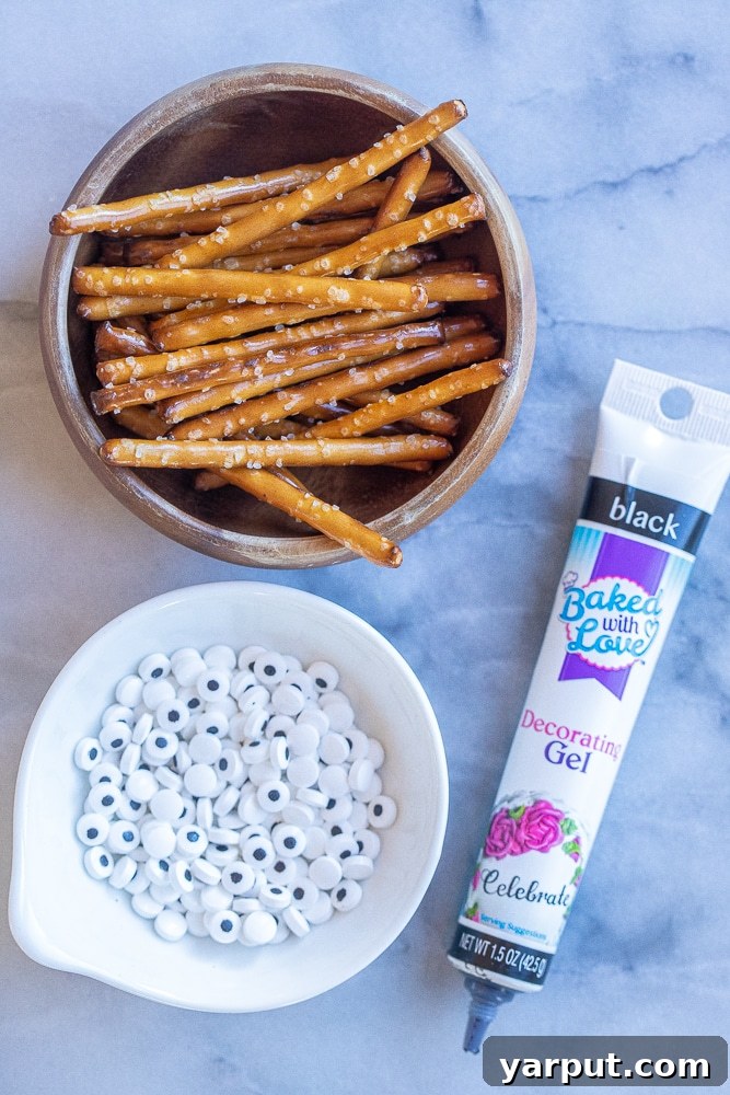 Spooky Smart Frankenstein Treats 5 A collection of decorating ingredients including pretzel sticks, candy eyes, and black decorating gel, essential for transforming healthy Halloween bars into cute Frankenstein treats.